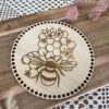 Couvercle rond en bois de 16 cm, gravé d’un motif abeille et nid d’abeille, avec trous pour fixation au crochet. Accessoire idéal pour projets DIY et artisanaux.