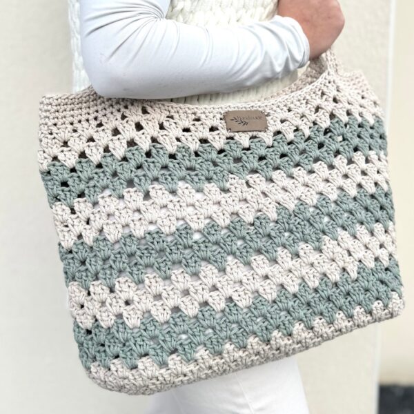 Sac en crochet granny beige et vert sauge porté sur l’épaule, réalisé avec le kit crochet Lou Pass