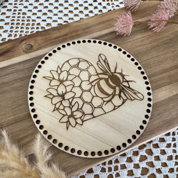 Couvercle rond en bois de 16 cm, gravé d’un motif abeille et nid d’abeille coeur, avec trous pour fixation au crochet. Accessoire idéal pour projets DIY et artisanaux.