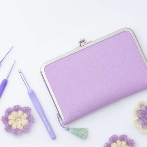 Set de crochets Tulip Etimo Murasaki lavande avec étui, ciseaux, aiguilles à laine et fleurs au crochet, présenté sur fond clair.
