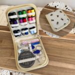 Kit de couture dans un étui rigide bleu avec motif bourdons, garni de fils, ciseaux, mètre ruban et accessoires essentiels.