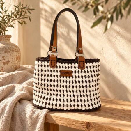 Sac London au crochet chocolat et écru, avec anses en cuir marron et attaches argentées.