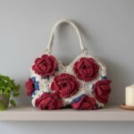 Sac au crochet fleuri fait main en collaboration LesPtitesBouill et Lou Passion, avec grandes roses rouges en relief et anses blanches.