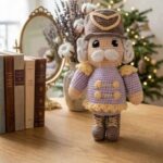 Casse-noisette de Noël au crochet fait main, en tenue mauve et dorée, réalisé avec le kit créatif Lou Passion.