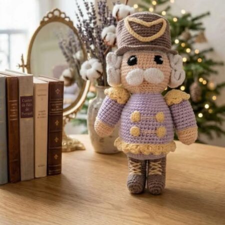 Casse-noisette de Noël au crochet fait main, en tenue mauve et dorée, réalisé avec le kit créatif Lou Passion.