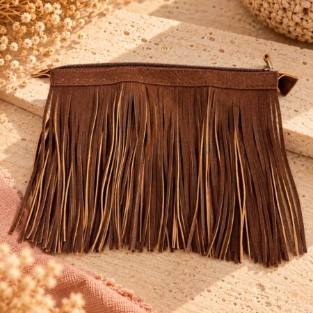 Fermeture à glissière en simili cuir cognac de 25 cm avec franges de 20 cm pour sac au crochet, sur fond travertin.